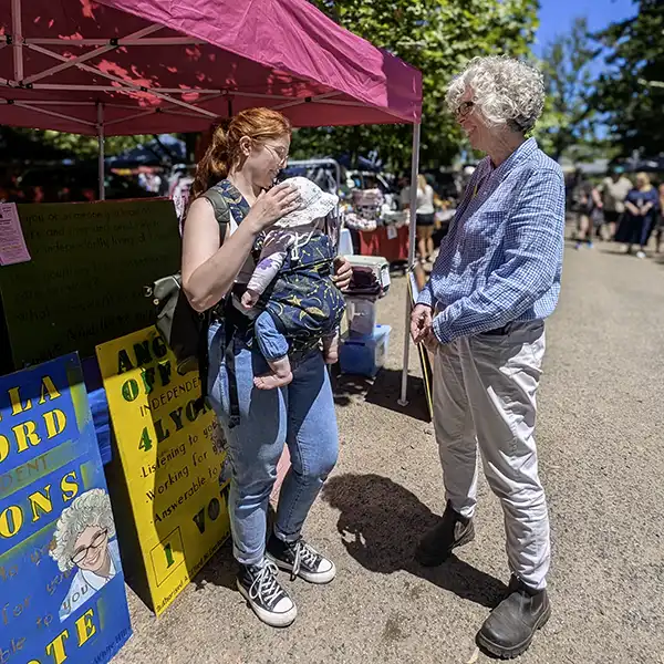 Angela Offord at the Evandale market talking with a young woman with a small child.